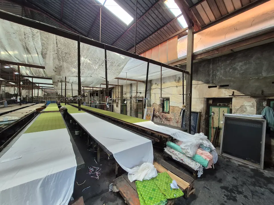 Proses persiapan kain di meja sablon batik untuk produksi seragam massal